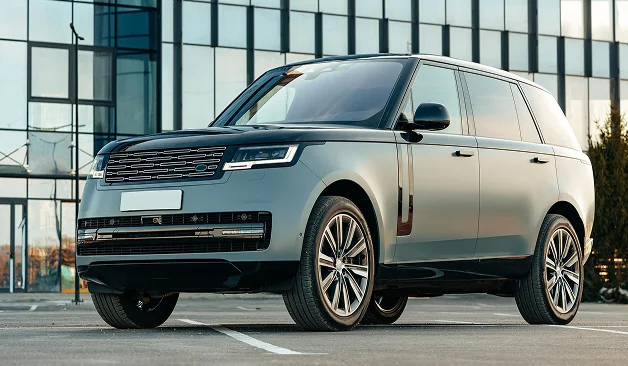 Modern gümüş Range Rover SUV, premium kentsel tasarımıyla bir ofis binasının yanında park etmiş.
